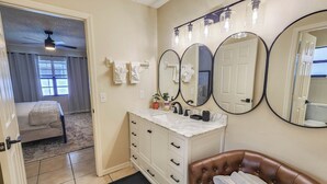 A bathroom with a vanity, mirrors, and a brown leather chair with towels. - Solar Heated Pool, Sleeps 10, Peaceful retreat close to shopping and beach! (Palm Coast)