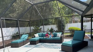 A covered outdoor area with a pool, a sectional sofa, and a lounge chair. - Solar Heated Pool, Sleeps 10, Peaceful retreat close to shopping and beach! (Palm Coast)