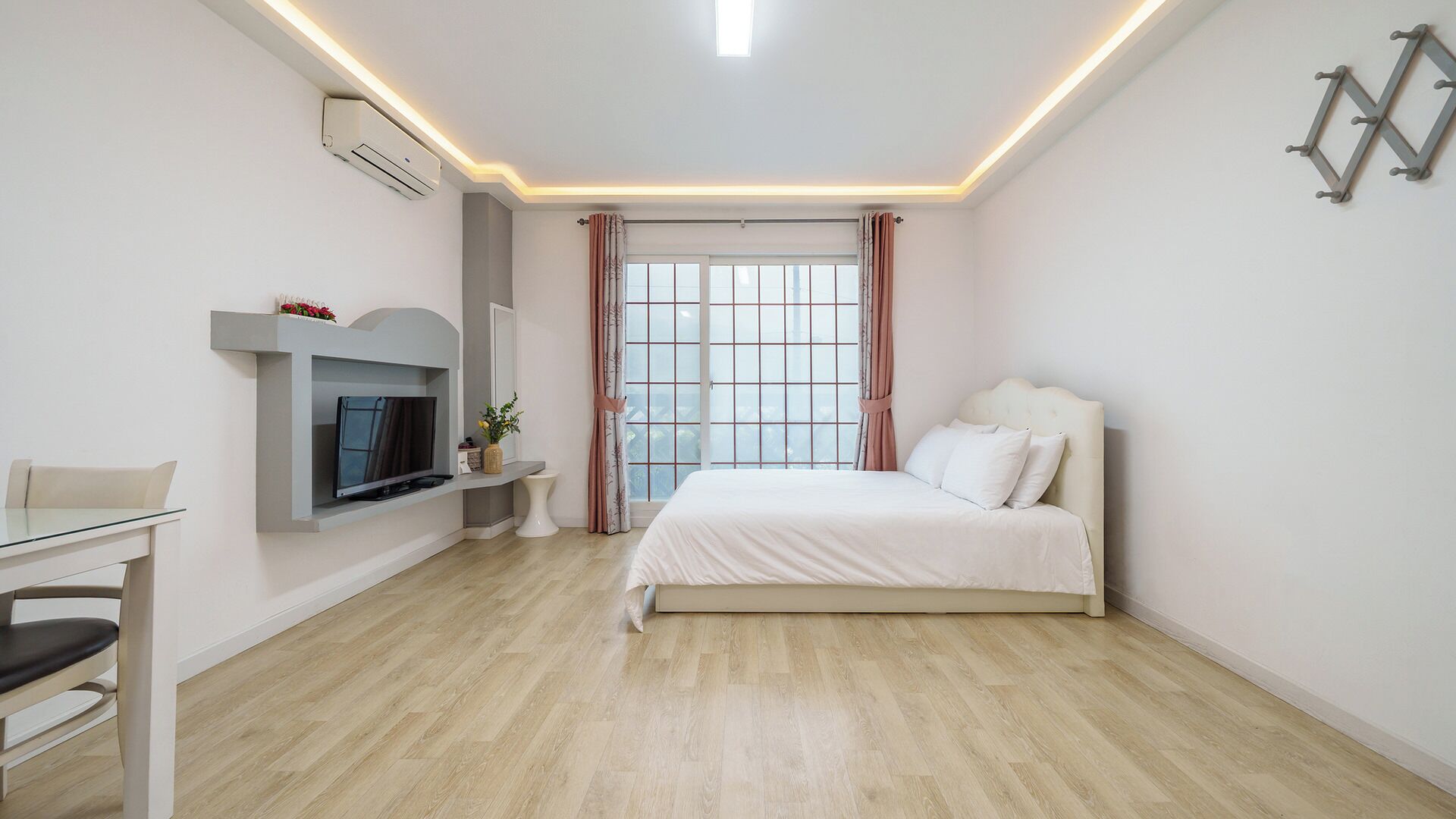 Una camera da letto moderna con un letto, una televisione e una finestra con tende.