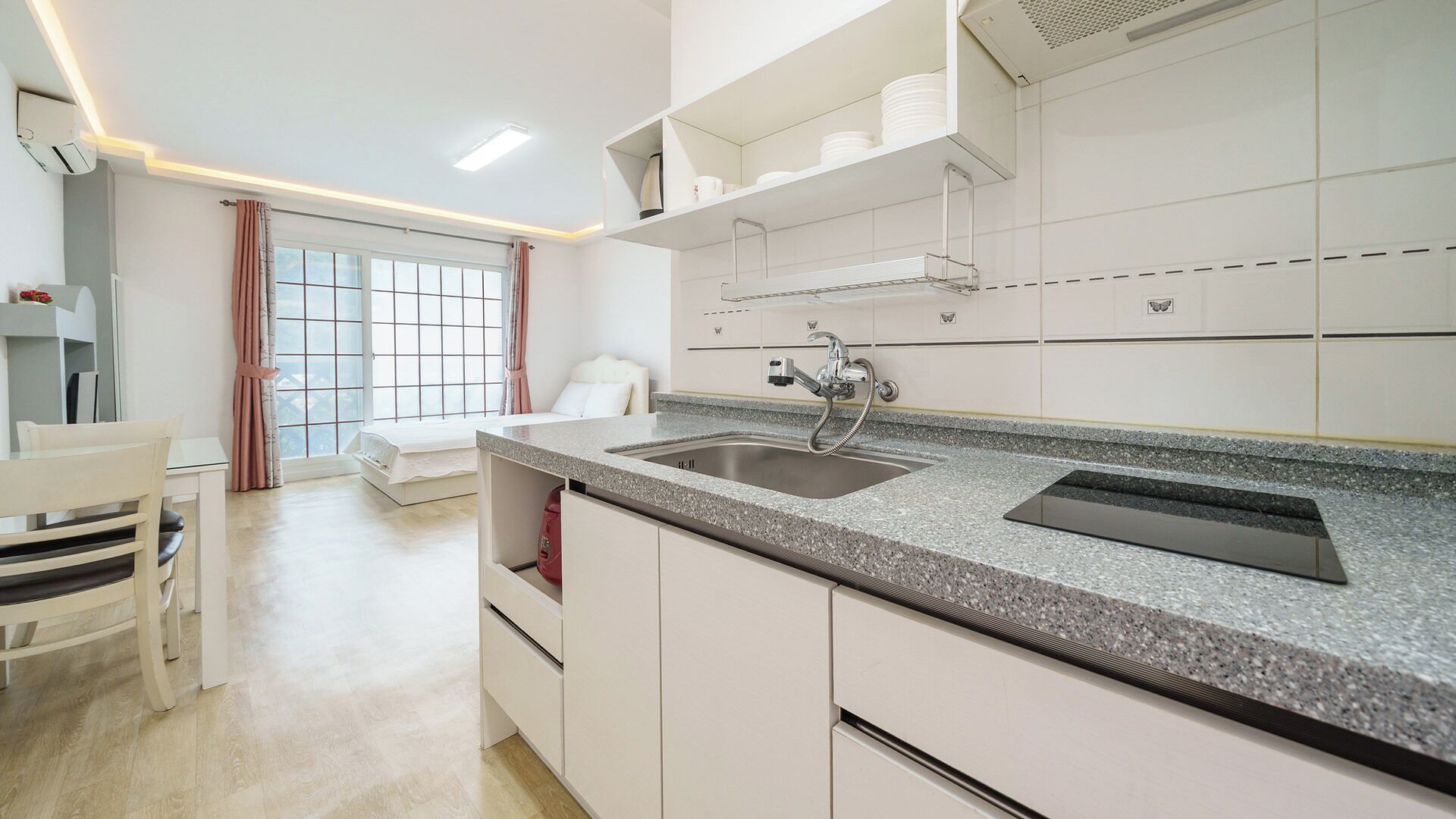 Una cocina moderna con encimera de granito, pileta de acero inoxidable y muebles blancos.