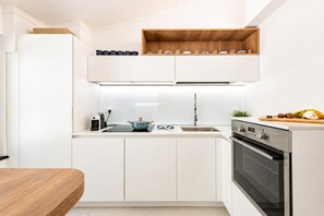 Een moderne keuken met witte kasten, een inbouwoven en een houten aanrecht.