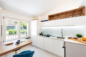 A modern kitchen with a dining area, a built-in oven, and a window with a view of greenery. - Wonderful House In Portofino With Parking (Portofino)