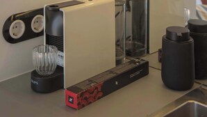 A kitchen area with a coffee machine, a kettle, and a water dispenser.