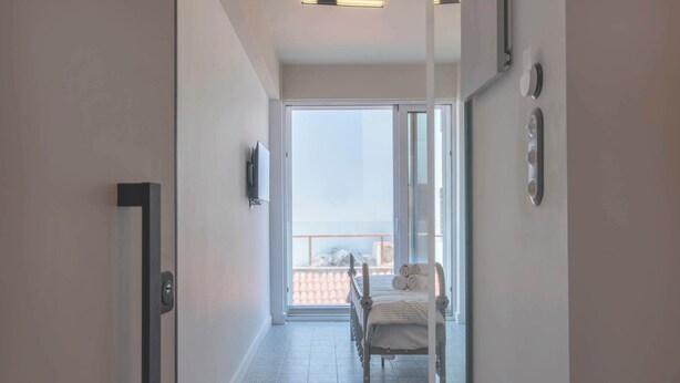 A hallway with a bed, a TV, and a balcony with a view.