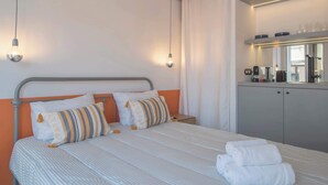 A neatly made bed with striped bedding, two pillows, and a set of folded white towels.