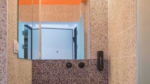 A bathroom with a rectangular sink, a mirror, and a door.