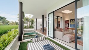 A modern outdoor living area with a pool, a sofa, and a dining table.