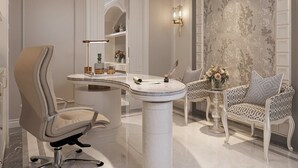 Une salle de bain luxueuse avec un meuble-lavabo en marbre, une chaise haute et un miroir décoratif.