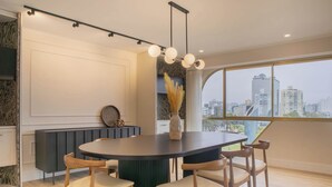 Ein moderner Essbereich mit einem runden Tisch, sechs Stühlen und Blick auf die Stadt durch große Fenster.