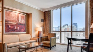 A hotel room with a large window, a sofa, a chair, a table, and a painting on the wall. - MGM Signature-30-619 Strip View Jacuzzi Studio (Las Vegas)