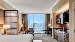 A hotel room with a large bed, a desk, a chair, a television, and a kitchen area. - MGM Signature-30-619 Strip View Jacuzzi Studio (Las Vegas)