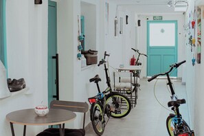 Passadís estret amb bicicletes aparcades a la paret, una taula amb una cadira i una porta amb la inscripció 'SORTIDA'.