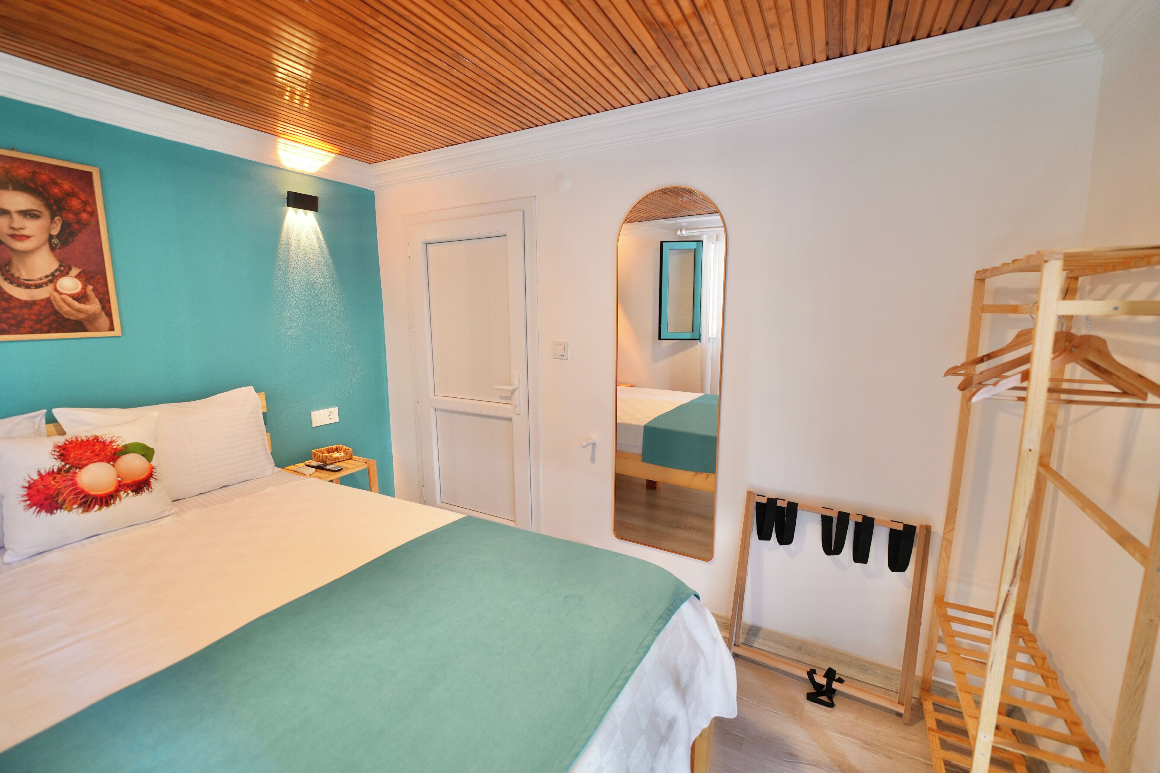 Una habitación de hotel con cama, mesita de noche, espejo y una estructura de madera.