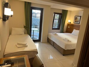 A hotel room with two beds, a desk, and a view of a balcony with a railing. - Fethiye Park Hotel (Fethiye)