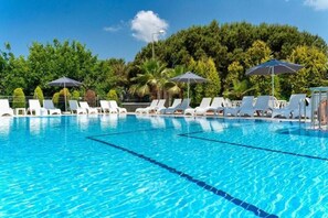 A swimming pool with white lounge chairs and umbrellas, surrounded by trees. - Fethiye Park Hotel (Fethiye)