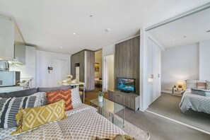 A modern hotel room with a sofa, TV, and a small table.