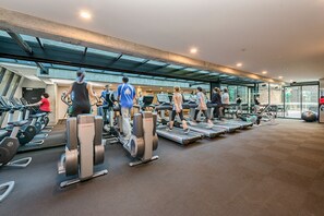 A modern gym with treadmills, stationary bikes, and weight machines.