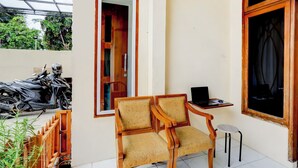 Una habitación con una silla de madera, una mesita con un ordenador portátil y una ventana.