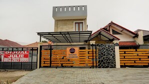 Propiedad resguardada por un muro de piedra, una puerta de madera y un letrero.