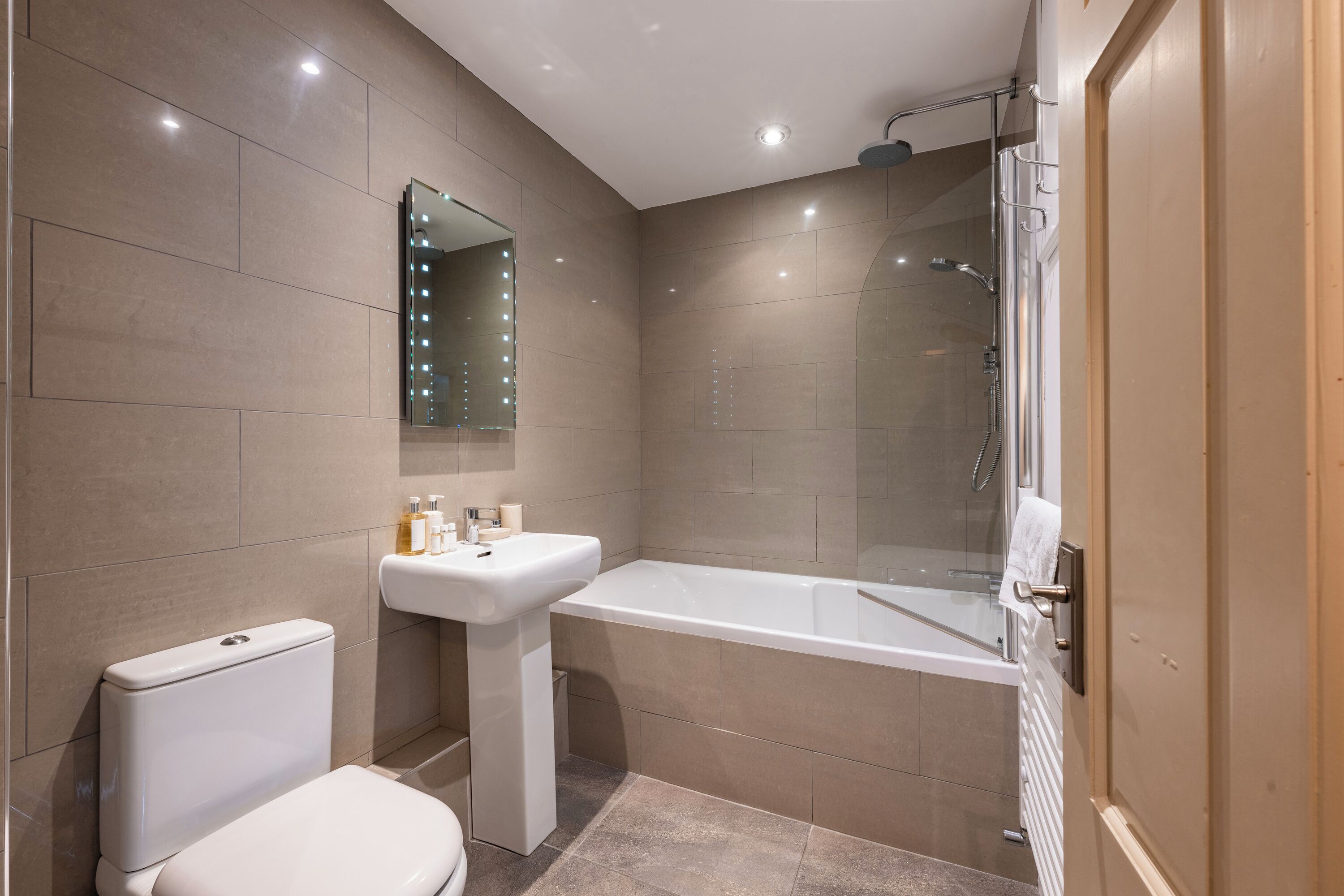 A modern bathroom with a toilet, sink, and glass-enclosed shower.
