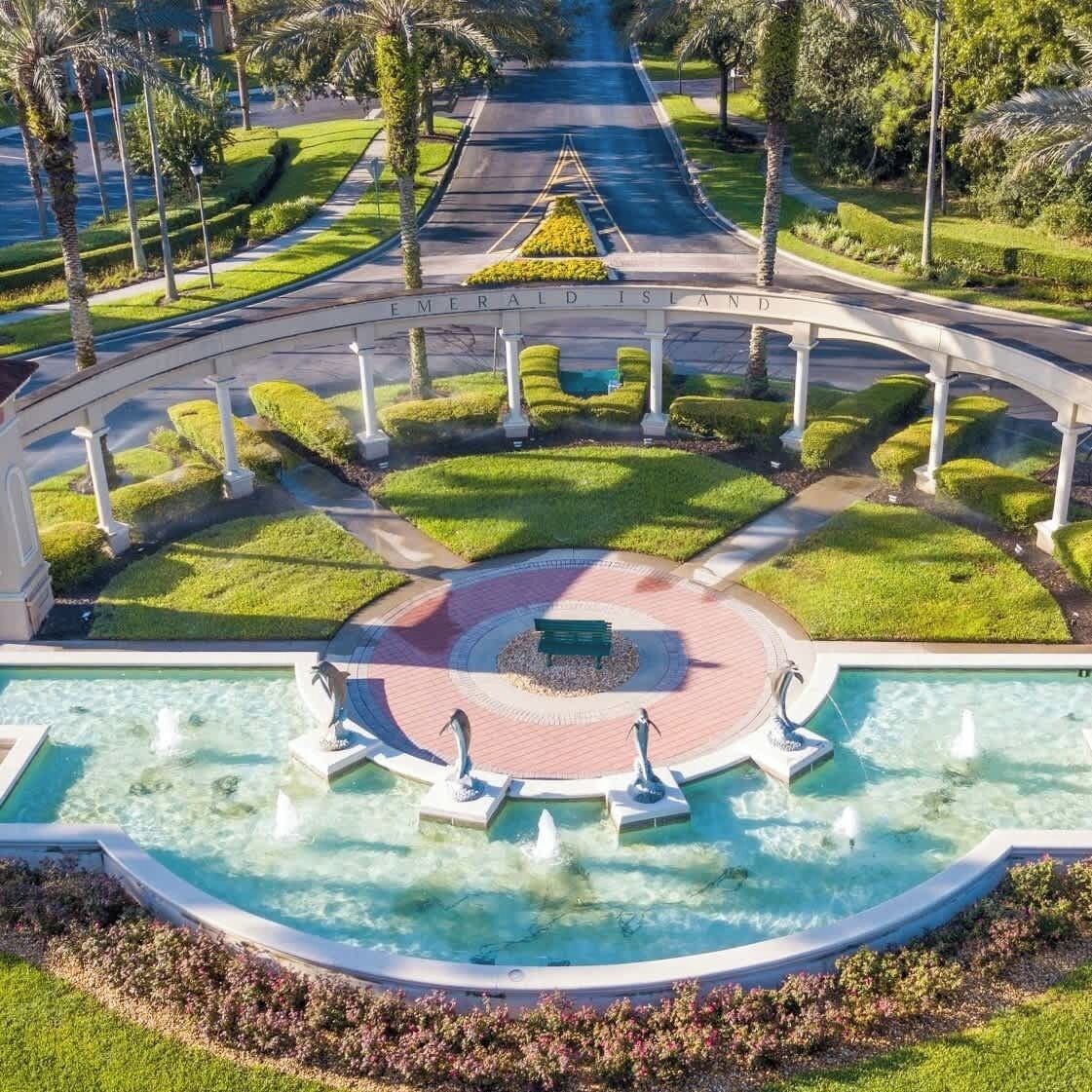 Un área ajardinada con una fuente central, un espacio de estar circular y un camino que lleva a un edificio con la leyenda "Emerald Island".