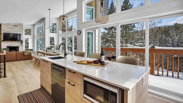 Una cocina moderna con una isla central, ventanas amplias y vistas a un paisaje nevado.