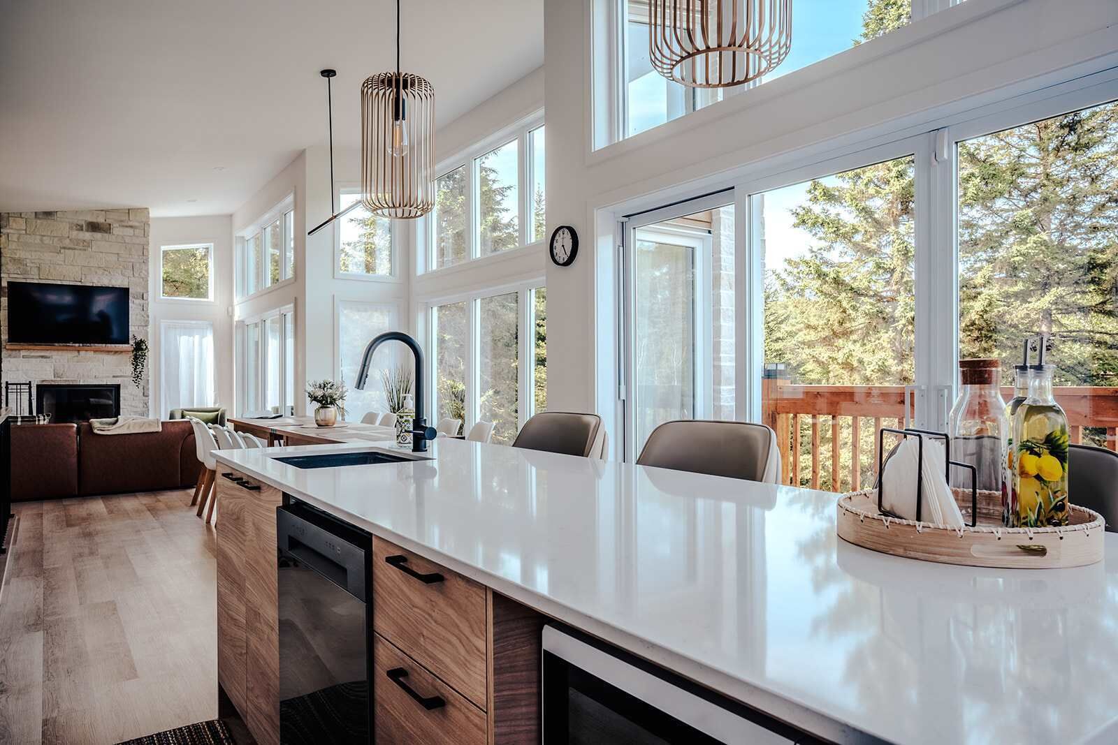 A modern kitchen with a large island, built-in appliances, and large windows offering a view of the outdoors.