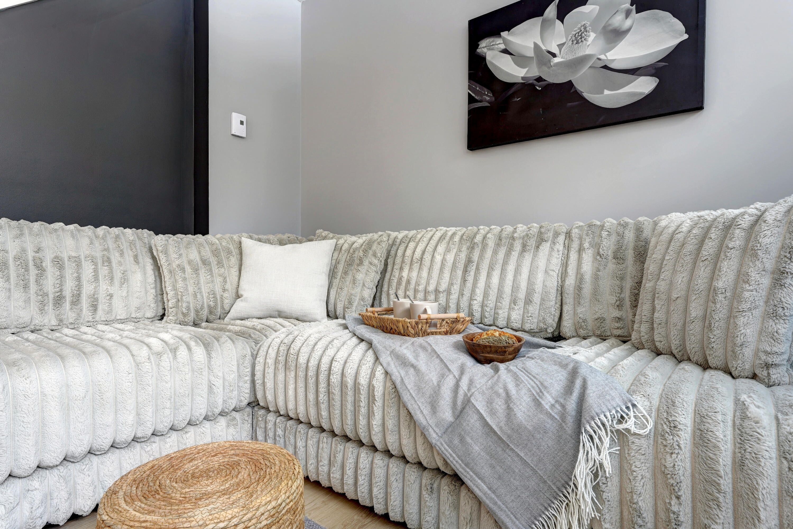 A modern living room with a textured sofa, a woven basket, and a wall-mounted artwork.