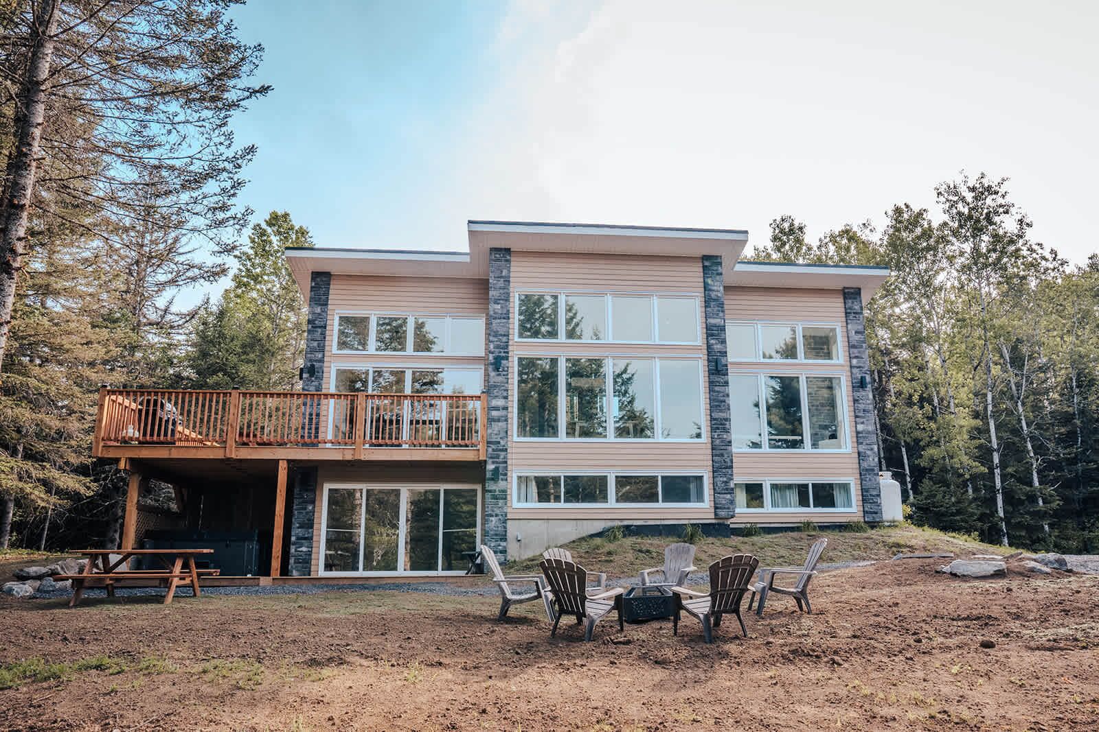 Une maison à deux étages dotée d’un balcon, de grandes fenêtres et d’une terrasse.