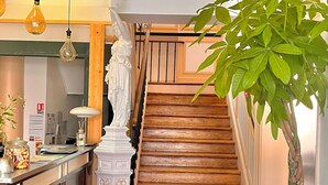 A kitchen with a checkered floor, a wooden staircase, and a potted plant. - hotel de la paix (Limoges)