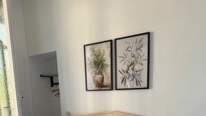 A neatly made bed with white linens, a remote control, and a rolled towel on the bed. There are two framed botanical prints on the wall above the bed. - hotel de la paix (Limoges)