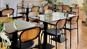 A dining area with multiple tables and chairs, a large potted plant, and a framed picture on the wall. - hotel de la paix (Limoges)