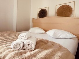Cama com cobertor fofo, duas almofadas e toalhas dobradas.