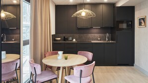 A modern kitchen with dark cabinets, a round table, and pink chairs.