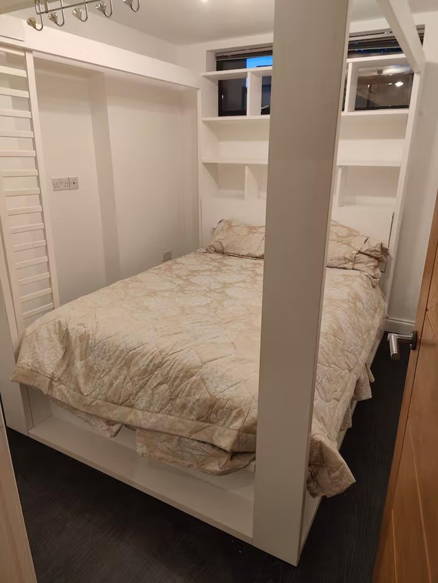 Une chambre à coucher avec un lit, des étagères intégrées et une fenêtre.