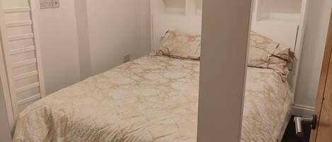 Une chambre à coucher avec un lit, des étagères intégrées et une fenêtre.