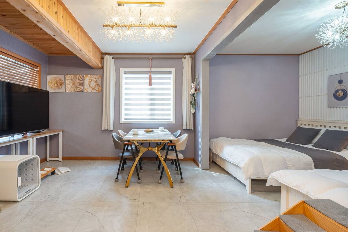 Una habitación moderna y bien iluminada con televisión, mesa de comedor y cama.