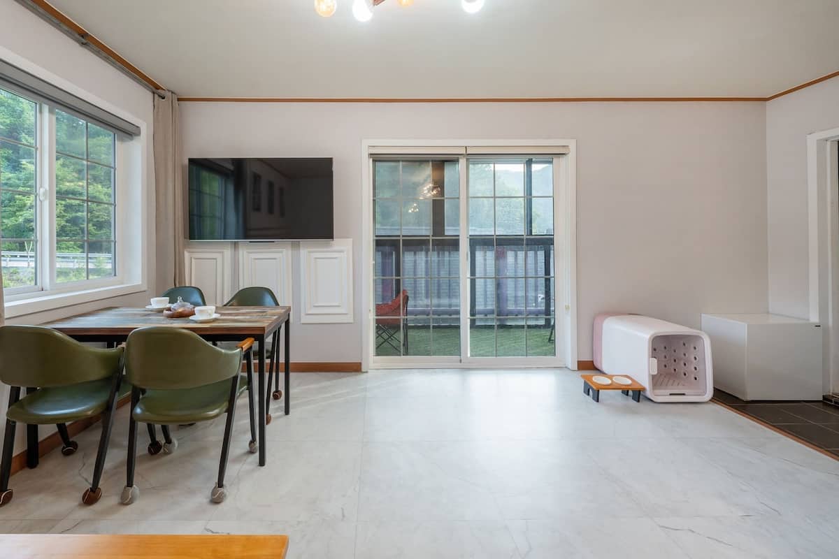 Un comedor con una mesa, sillas, un televisor y un ventanal corredera que da a un balcón.