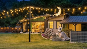 Une maison moderne avec une façade en verre, un espace extérieur aménagé et une grande statue de chien.