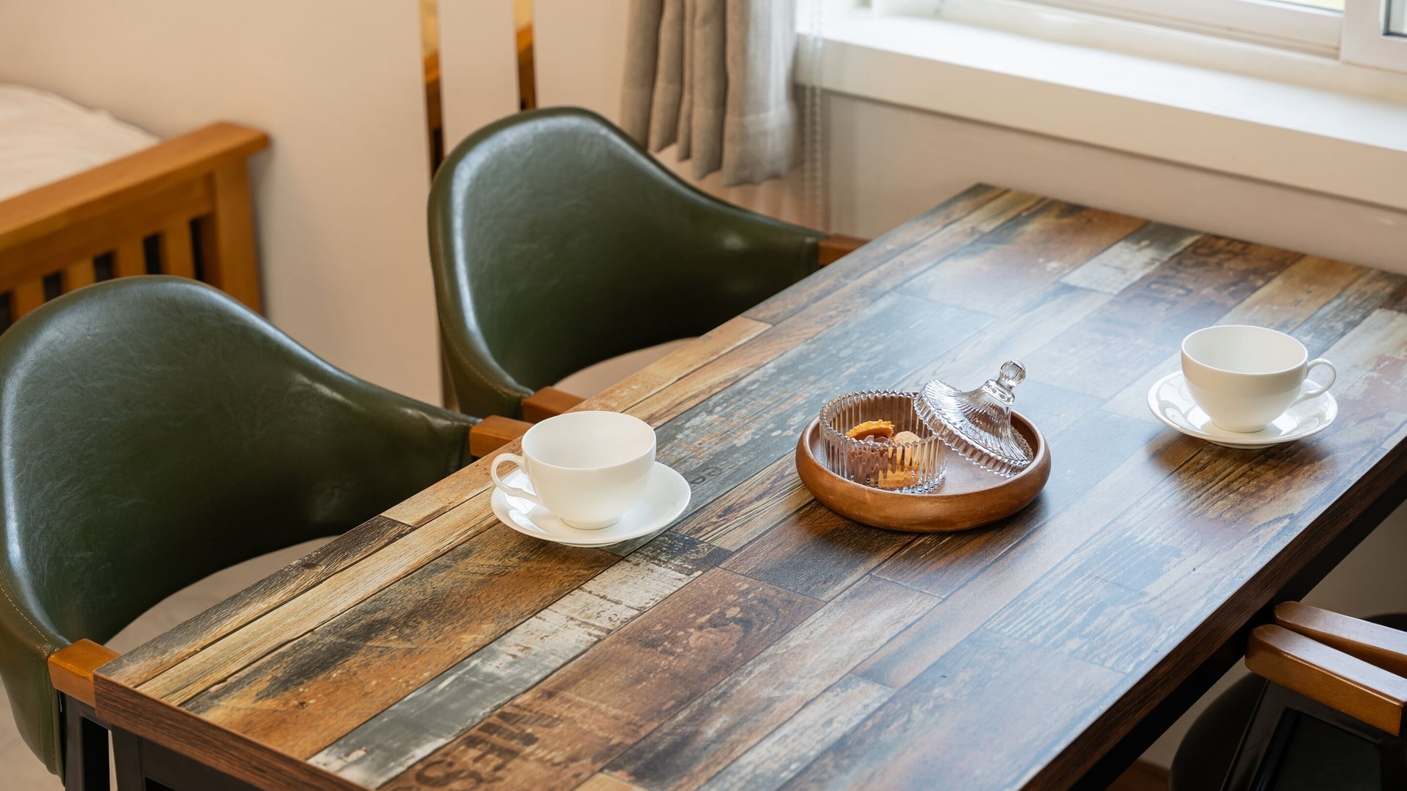 A wooden table with two white cups and a sugar bowl.