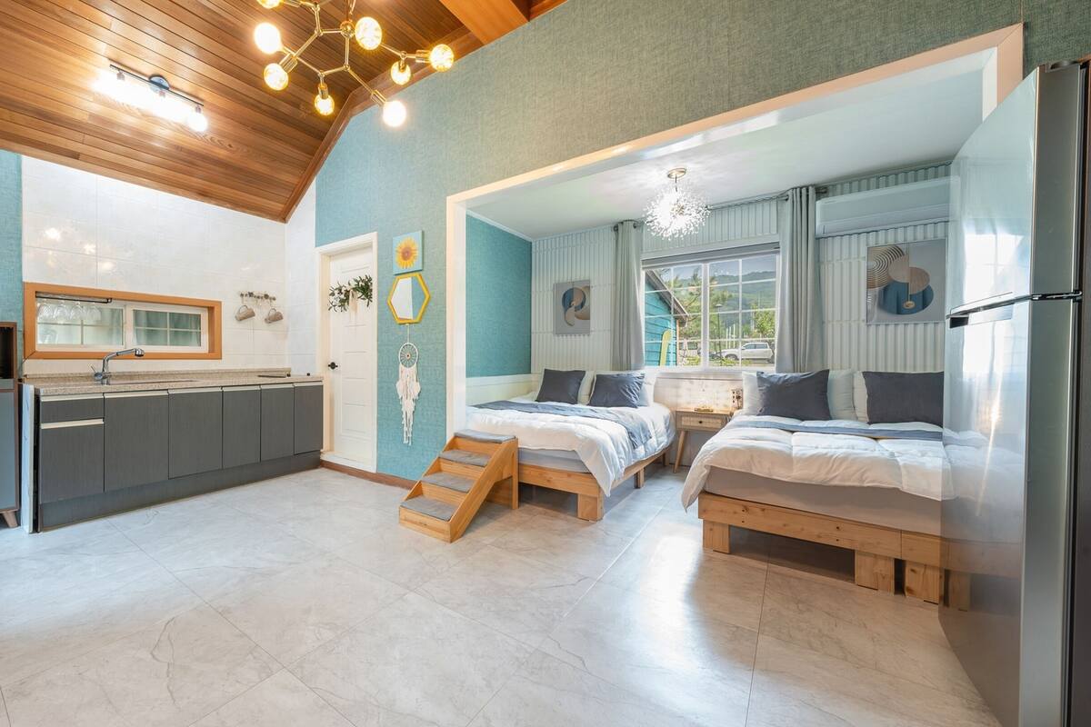 Un espacio habitable moderno y funcional, con cocina, dos dormitorios y un ventanal que proporciona luz natural.