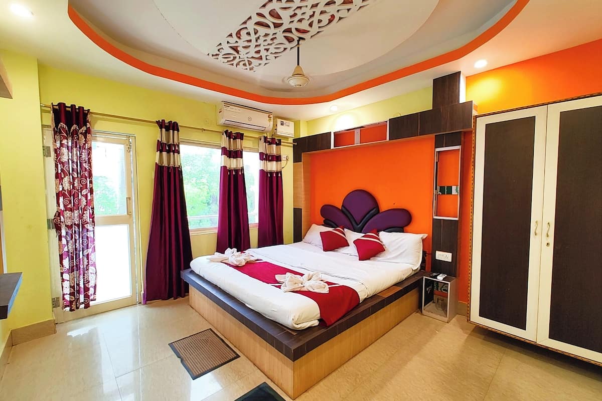 Une chambre d’hôtel comprenant un lit, des rideaux, un appareil de climatisation, une armoire et un décor au plafond.