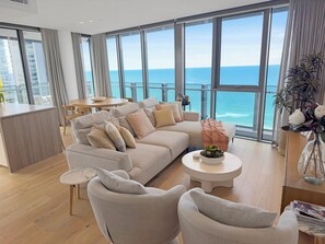 Una sala de estar moderna con un sofá grande, una mesa de centro y vistas al océano.