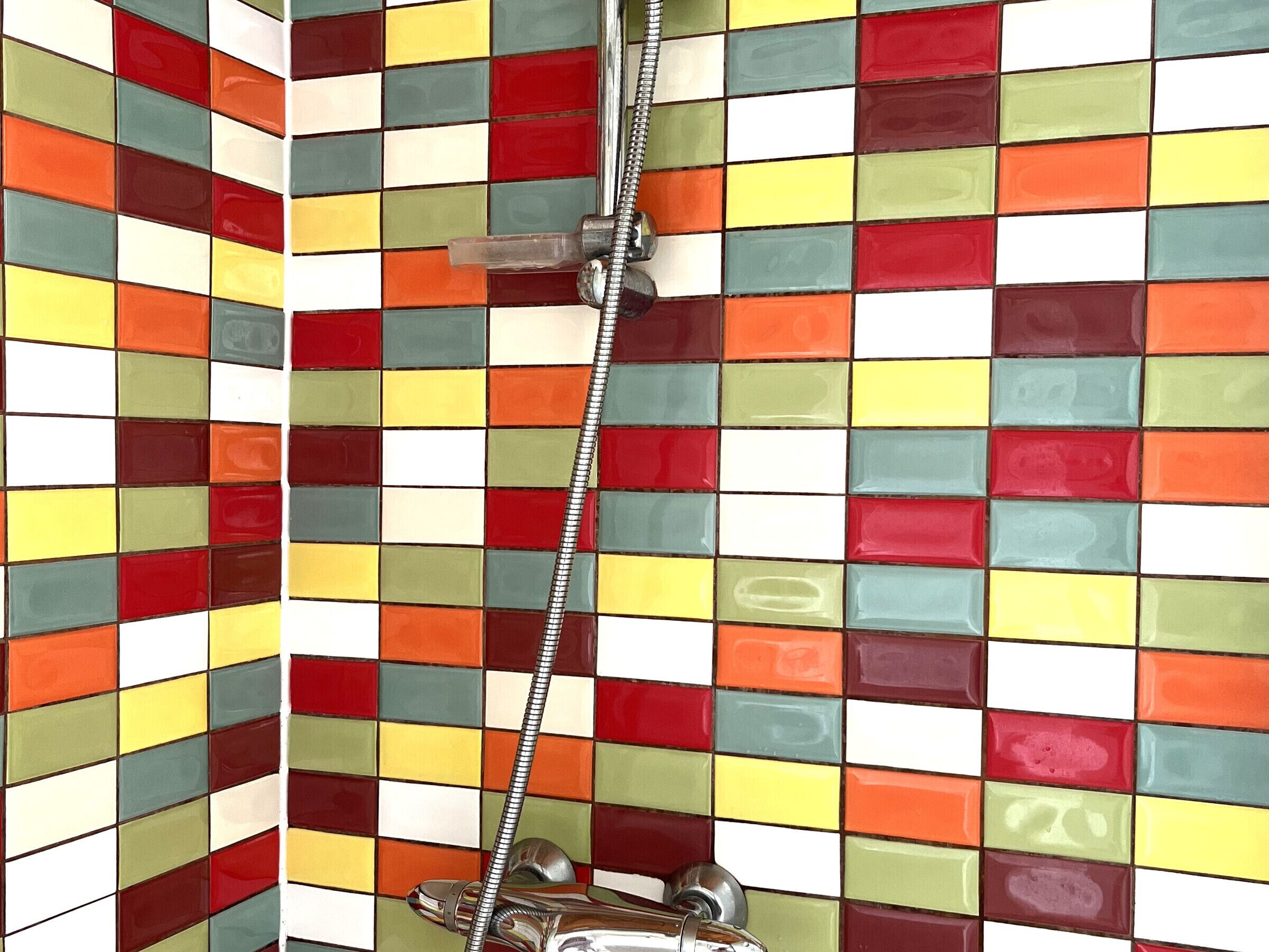 A bathroom with a tiled wall featuring a multicolored checkered pattern.