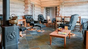 A cozy log cabin interior with a fireplace, leather chairs, a wooden table, and a tiled floor. - "Mojag" - 900m from the sea by Interhome (Hirtshals)