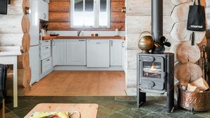 A cozy cabin interior with a kitchen area featuring white cabinets, a wooden countertop, and a wood-burning stove. - "Mojag" - 900m from the sea by Interhome (Hirtshals)