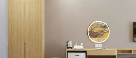 Een moderne kamer met een houten garderobe, een bureau met een computer, een kleine koelkast, en een zithoek.