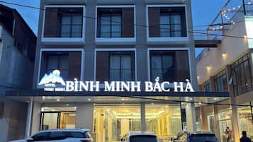 En høj bygning med hotel, moderne facade, store vinduer og et tydeligt skilt.