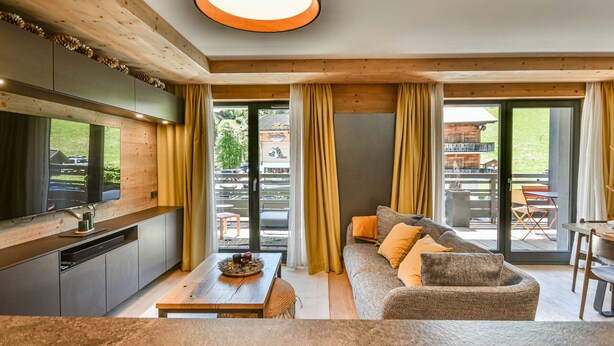 A modern interior with a kitchen, dining area, and a sofa with a view to the outside.