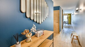 A hallway with a wooden bench, a wall-mounted mirror, and a decorative vase with dried flowers.
